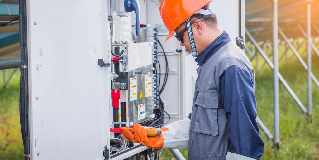 7885446 Licensed electrician working on a residential or commercial electrical panel while wearing safety gloves and protective equipment