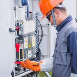 Licensed electrician working on a residential or commercial electrical panel while wearing safety gloves and protective equipment