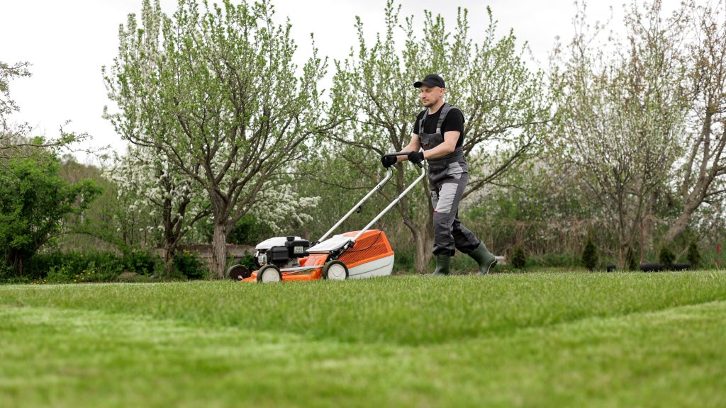 Landscaping supervisor providing hands-on staff training to a crew member on proper equipment use and worksite safety practices