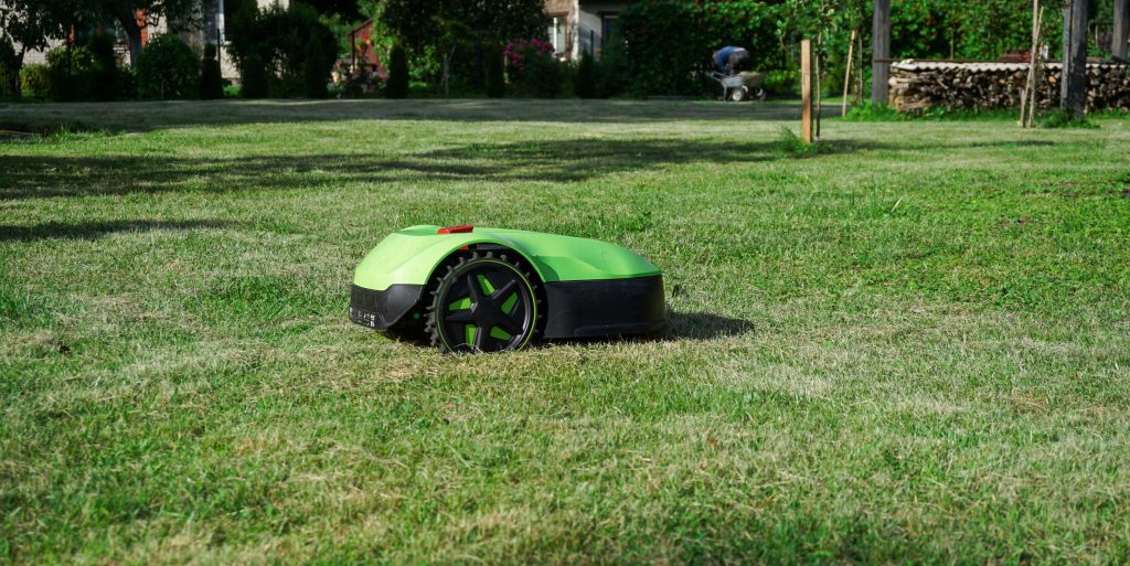 Electronic robotic lawn mower, trimming grass in the yard. Garden equipment.