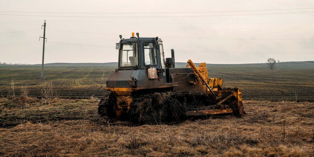 A bulldozer in a field in mud in cloudy weather