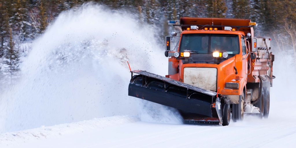 Snow plow clearing road after winter snow storm an orange truck with a snow plow on the front