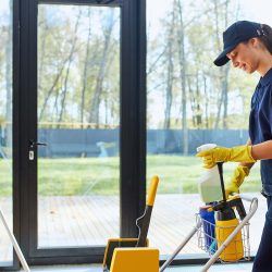 Janitorial worker mopping a commercial hallway floor with a professional mop and bucket with wet floor safety signs visible