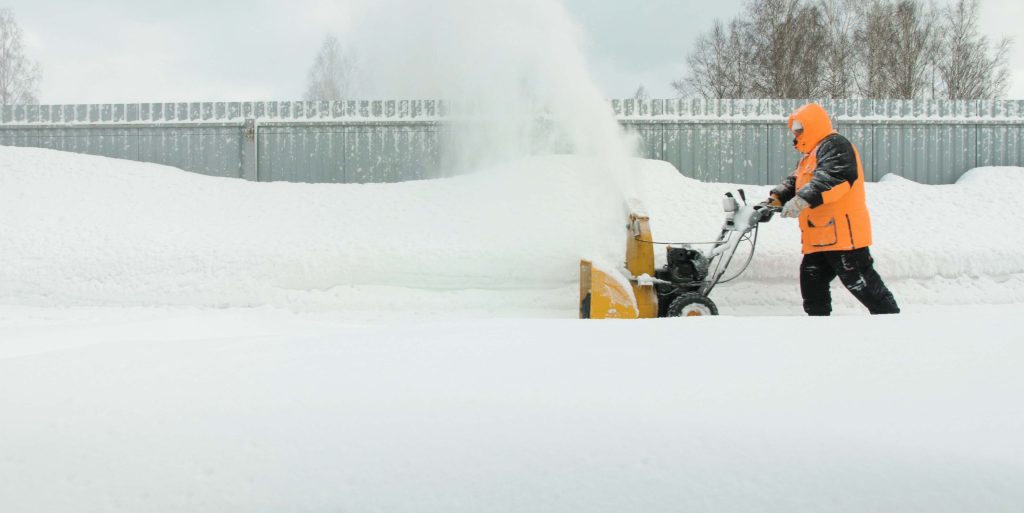Man cleans snow with a snow thrower goes right to left