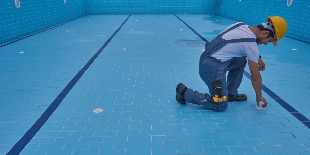 Repairman is repairing pool with equipment. Pool maintenance sty Swimming pool contractor reviewing permits and blueprints at a pool construction site before beginning installation work
