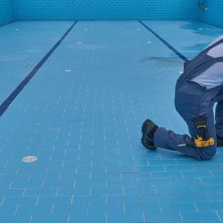 Swimming pool contractor reviewing permits and blueprints at a pool construction site before beginning installation work