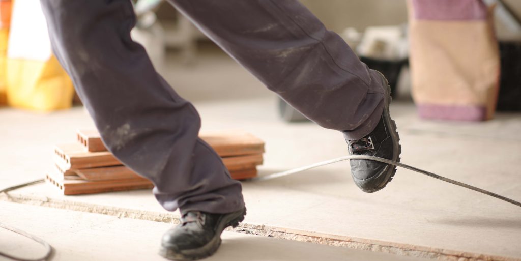 Construction worker stumbling with a cord