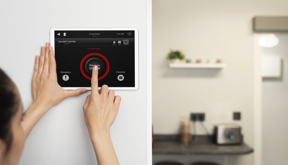Security system technician installing an alarm control panel on a wall inside a residential or commercial building