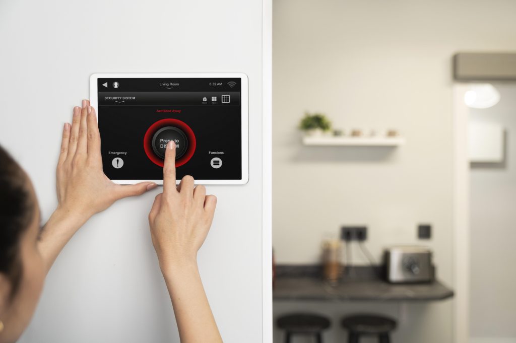 Security system technician installing an alarm control panel on a wall inside a residential or commercial building
