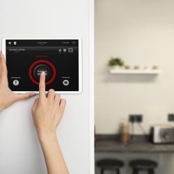 Security system technician installing an alarm control panel on a wall inside a residential or commercial building