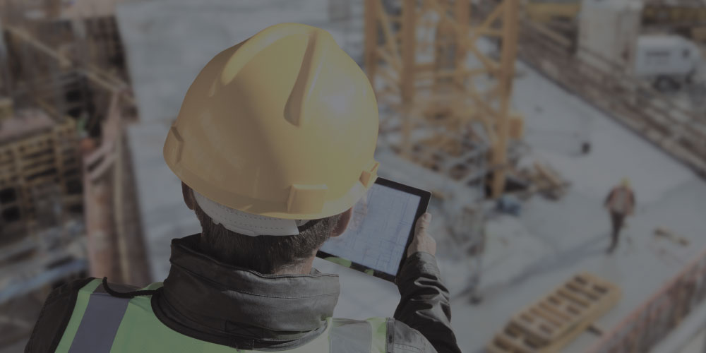Construction worker looking at model of site on a tablet