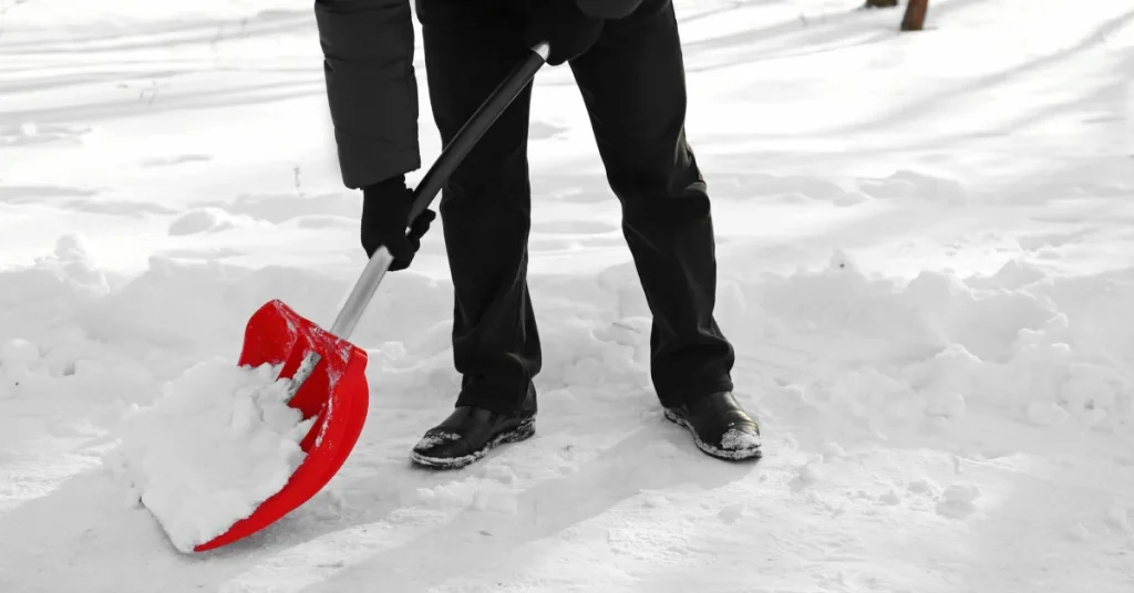 A worker clearing snow with a red shovel under a snow removal contract A worker clearing snow with a red shovel under a snow removal contract