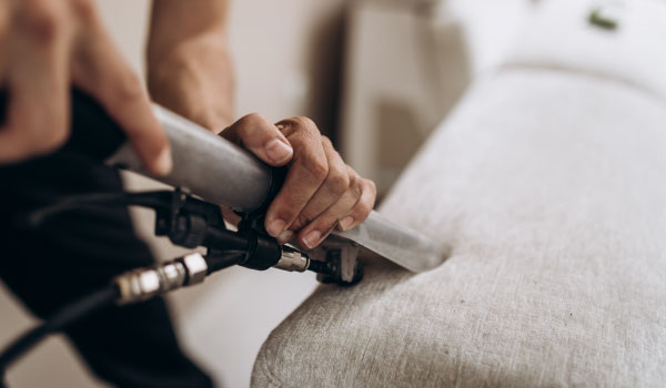 maintenance-vacuuming-sofa Maintenance worker vacuuming a sofa
