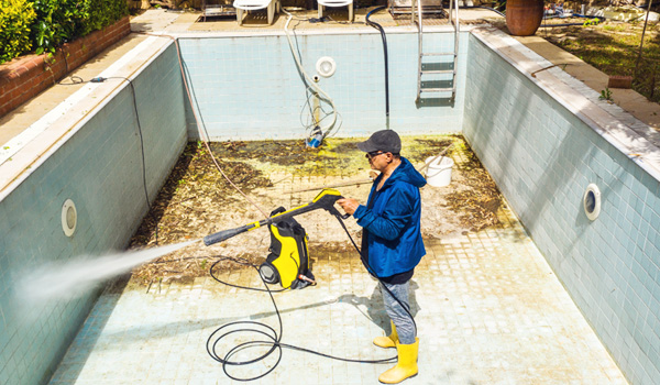 shutterstock_1733178965 Pool contractor cleaning pool with power washer