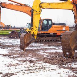Construction equipment sits idle on a snow-covered site, highlighting the challenges of winter construction delays and cold-weather project risks.