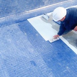 Pool construction contractor laying down tile