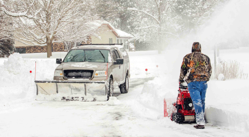 shutterstock_252278269 Pickup truck and landscaping worker plowing snow