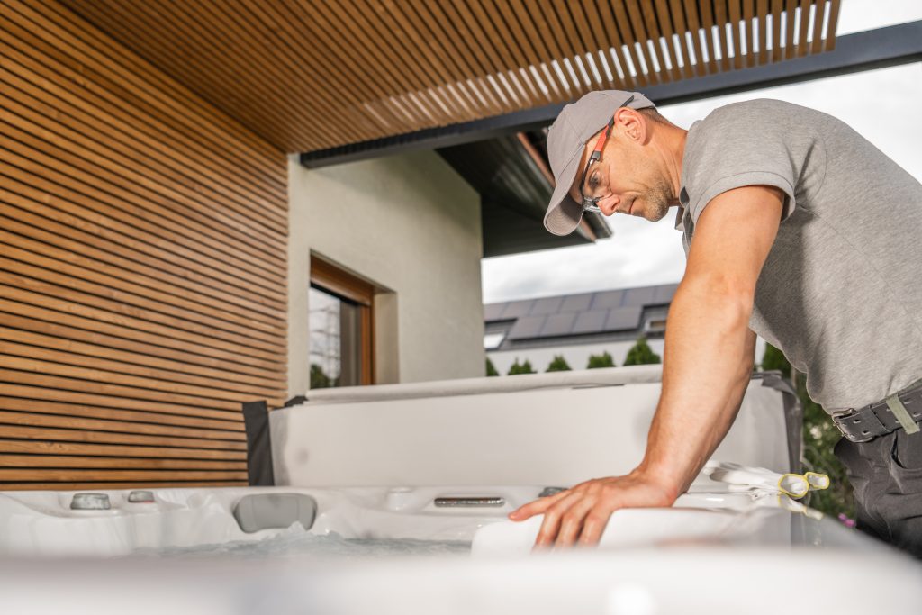 Contractor carefully inspecting swim spa installation components during outdoor residential setup.