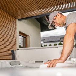 Contractor carefully inspecting swim spa installation components during outdoor residential setup.