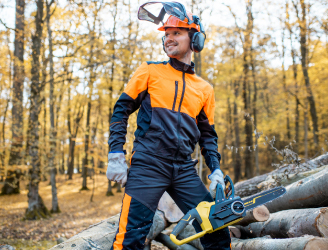 Smiling arborist with chainsaw in wooded area